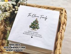 a paper napkin with a christmas tree on it sitting in a basket next to flowers