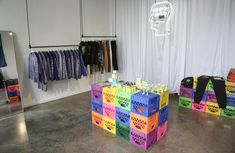 colorful boxes are stacked on top of each other in front of a white wall with clothing hanging