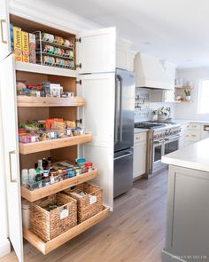 a kitchen with white cabinets and wooden shelves filled with food items on top of them