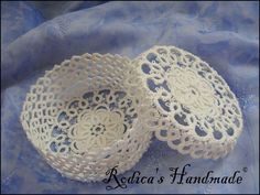 two white crochet baskets sitting on top of a blue cloth