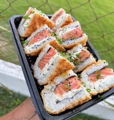 sushi is being served on a black tray