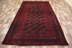 an old red rug on the floor in a room with tile floors and wooden walls