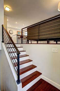 there is a stair case on the wall next to the stairs in this house with wood floors and white walls