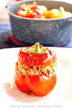 a white plate topped with tomatoes covered in rice next to a bowl of vegetables on the side