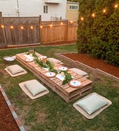 a table set up in the middle of a yard with plates and place settings on it