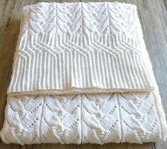 two white knitted blankets sitting on top of a wooden floor