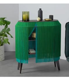 a green cabinet sitting next to a potted plant and a black chair in front of it