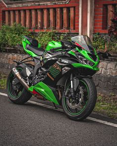 a green and black motorcycle parked on the side of the road next to a building