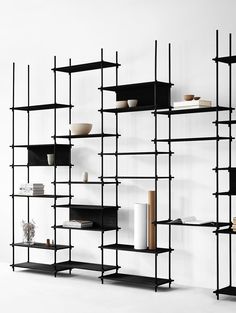 a black shelf with shelves and vases on it in front of a white wall