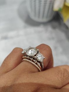 a woman's hand holding three rings with diamonds