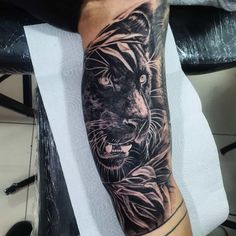 a man's arm with a black and grey tiger tattoo on the left forearm