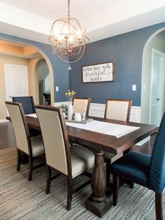 a dining room table with blue chairs and a chandelier hanging from the ceiling