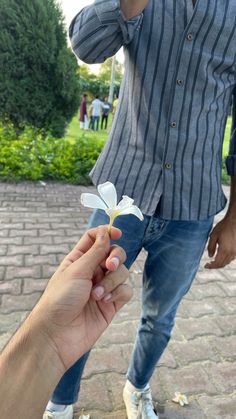 a person holding a small white flower in their hand while another person holds it up