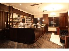 a bar with several people behind it in a dimly lit room, and lights hanging from the ceiling