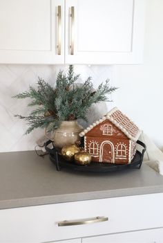 a gingerbread house on a platter with christmas decorations in the kitchen countertop