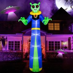 an inflatable alien character is standing in front of a house with purple and green lights