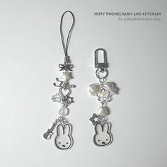 two keychains with charms attached to them on a white surface, one has a bunny face and the other has a bow