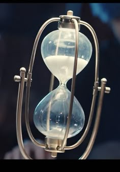 an hourglass is sitting on top of a metal stand with two glass balls in it