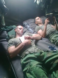 two men laying down reading books in the dark