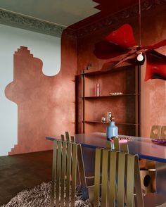 a dining room table with chairs and a ceiling fan in the middle, next to a bookcase