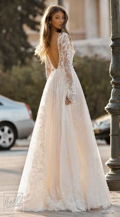 a woman in a wedding dress standing next to a lamp post and looking back at the camera