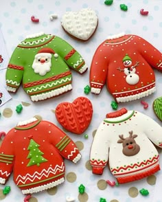 decorated cookies are arranged on a table with christmas sweaters and mittens, including an ornament