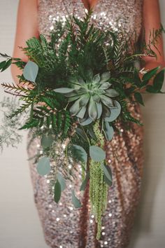 a woman in a sequin dress holding a bouquet of greenery