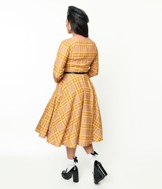 Made from a cozy knit fabric and featuring a vibrant mustard yellow plaid print, this 1950s style swing dress is an absolute stunner. The surplice neckline adds a touch of elegance while the quarter sleeves keep it classy and comfortable. Accessorized with a removable black belt that cinches in at the waist for that perfect hourglass silhouette. And can we talk about the added size pockets? Don't worry about struggling with zippers either; this dress comes with a convenient back zipper for easy Can We Talk, Hourglass Silhouette, 1950s Style, Surplice Neckline, Keep It Classy, Yellow Plaid, Cozy Knit, 1950s Fashion, Plaid Print