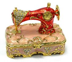 a red sewing machine sitting on top of a pink box with gold trimmings