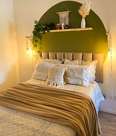 a bed with pillows and blankets on top of it next to a green headboard