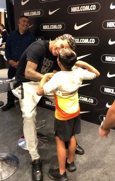 a man and child are standing in front of a wall with nike logos on it