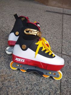 two roller skates with yellow and red laces sitting on the ground next to each other