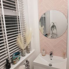 a white sink sitting under a bathroom mirror next to a window with blinds on it