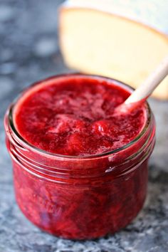 a jar filled with red liquid sitting on top of a counter next to a piece of bread