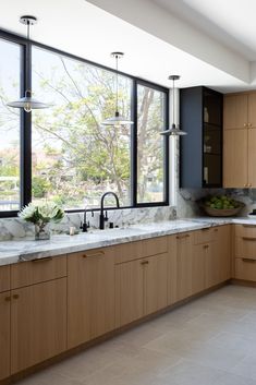 a large kitchen with marble counter tops and wooden cabinets, along with an open window