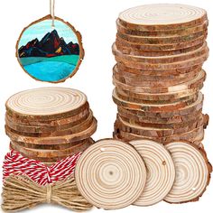 a pile of wood slices next to a round ornament with a mountain scene on it