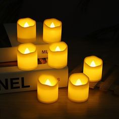 five lit candles sitting on top of a table next to a book and remote control