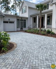 a brick driveway in front of a white house