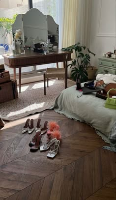 shoes are laying on the floor in front of a mirror and desk with a large window