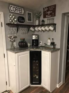 a kitchen with white cabinets and shelves filled with wine glasses on top of the counter