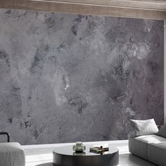 a living room with grey marble walls and furniture in the corner, along with a round coffee table