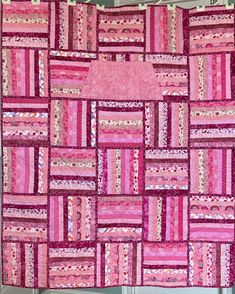 a pink quilt is hanging on the wall