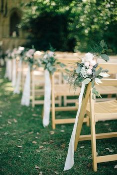 rows of wooden chairs with white sashes and flowers tied to the back of them