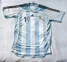 a blue and white soccer jersey laying on top of a bed