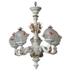 a white chandelier with three lights hanging from it's sides and cherubs on the top