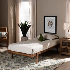 a bed sitting next to a window in a bedroom on top of a wooden floor