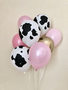 a bunch of balloons with black and white cow print on them