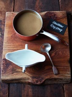 there is a cup of coffee and spoons on the wooden tray next to it