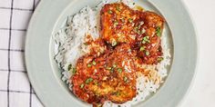 a white plate topped with rice and meat covered in sauce on top of a checkered table cloth