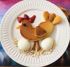 a white plate topped with pancakes and eggs on top of a wooden table next to a painting